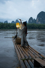Hanfu Girl holding a lantern on a bamboo raft, Xingping, China. Vertical