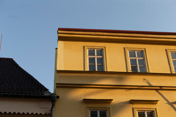 A vibrant yellow building stands tall, beautifully contrasting with the clear blue sky that serves as a perfect backdrop for it