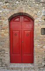 Red door in archway of brick building