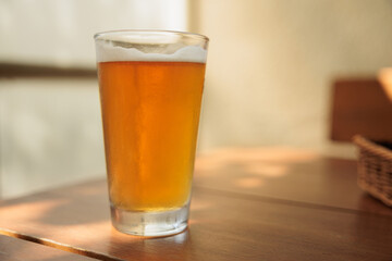 grande bicchiere riempito con della birra fresca, su un tavolo di legno, di giorno