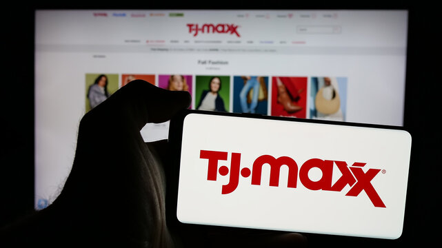Stuttgart, Germany - 10-04-2024: Person holding smartphone with logo of US discount department store company TJ Maxx on screen in front of website. Focus on phone display.
