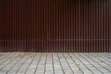 Fragment of empty street city, brown wall of fence and pavement. Building facade. Mockup or background for creativity. Place for advertising, banner, billboard, announcement, poster.
