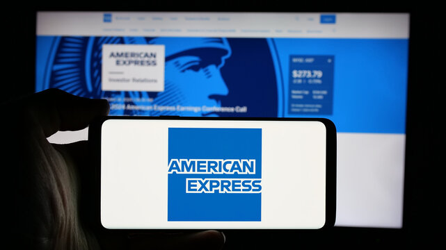 Stuttgart, Germany - 10-08-2024: Person holding cellphone with logo of US business American Express Company (Amex) on screen in front of business webpage. Focus on phone display.