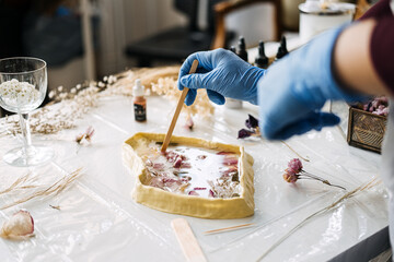 Crafting with resin and dried flowers, using a wooden stick to create detailed art pieces. Essential tips for making unique and visually appealing resin art.