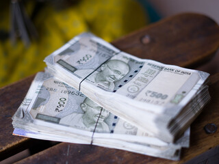 a hand holds multiple bundles of ₹500 Indian rupee notes, neatly stacked and tied with rubber bands, showcasing financial abundance and control over wealth. 