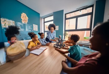 A teacher and group of children are gathered around a small robot on a table in a classroom.