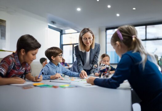 A teacher guides young students in a classroom as they work on a project involving a robot toy. - Powered by Adobe