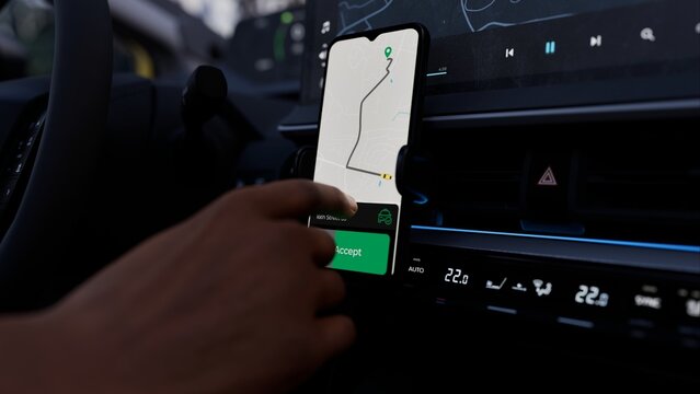 A taxi or ride-share driver uses an app to accept a passenger request. The phone screen shows a map and route, demonstrating the app's functionality for managing rides and navigating efficiently