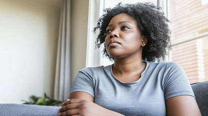 Fototapeta premium Pensive young woman sitting indoors, thoughtful expression and natural light for quiet contemplation. Calm and reflective atmosphere in a casual home setting for introspection and personal reflection.