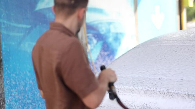 Cleaning car using active foam. Handsome man washing his luxury car on self car-washing