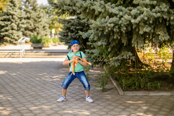 cheerful young boy with glasses and bandana, in green top and denim shorts playing with a toy monkey