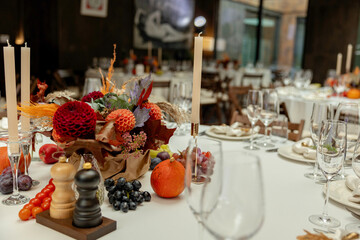 Aesthetic stylish autumn table setting background, arranged flowers and candles under natural light.