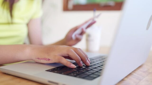 A woman is typing on a laptop while holding a credit card. Concept of modern technology and convenience, as the woman is able to make a purchase with just a few clicks on her laptop