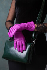 A woman in bright fuchsia gloves hold a small green handbag