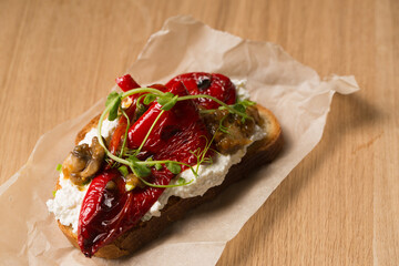 Sandwich with cheese spread, mushrooms, grilled pepper and microgreen on a wooden table