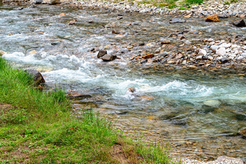 Rushing Shimagawa river stream with pebbles and grass-covered banks, Shima Onsen, Gunma, Japan. October 2024