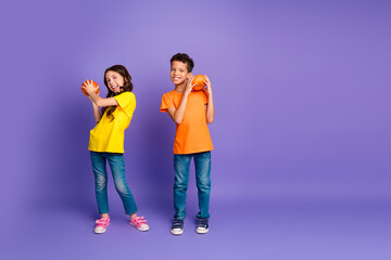 Naklejka premium Full size photo of charming two little children hold cute pumpkins wear trendy orange yellow outfit isolated on violet color background