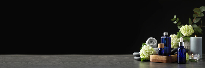 Composition with cosmetic products for spa treatment on table against black background, banner design. Space for text