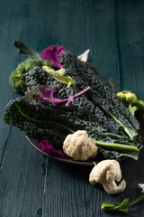A plate of vegetables including cauliflower, and kale on a wooden table