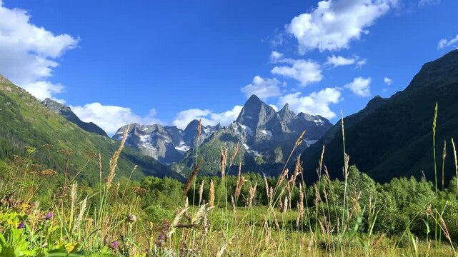 Teberdinsky Nature Reserve. View of Kosygin's glade in the Gonachkhir gorge and the top of Dombai-Ulgen mountain near LakeTumanly-Kel on a sunny sum mer day. Panoramic landscape. Resort. 4K