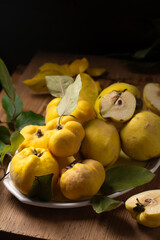 Ripe yellow quince fruits on a plate on a wooden board