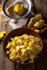 Prepared quince in a bowl for making jam on an wooden table
