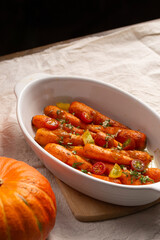 Blush carrots with sauce in a white ceramic dish baked in the oven. A delicious dish for Thanksgiving