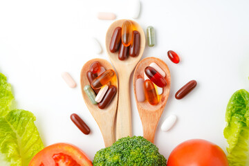 Colorful pills and capsules in wooden spoon with fresh vegetables, Vitamins and supplement
