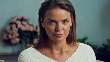 Feelings of passion, flirtation and excitement. Woman is displaying a range of facial expressions in slow motion. She is in a living room with flowers in the background