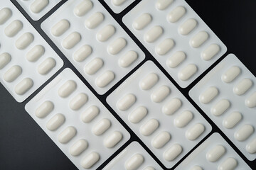 Pills Medicine tablet capsules in blister pack on a black background