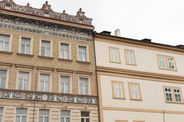 A large and prominent building that features a significant number of windows is situated directly adjacent to a smaller, more modest building