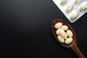 white softgels in wooden spoon, capsules with vitamin E, Cod liver oil, DHA, Fish oil omega 3