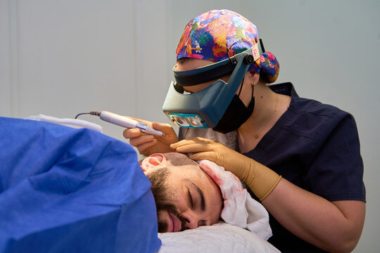 Surgeon conducting hair transplant on resting patient