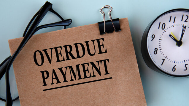 OVERDUE PAYMENT - words on brown paper on a light background with glasses and a clock