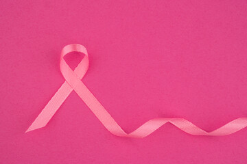 Pink ribbon on a vibrant pink background symbolizes breast cancer awareness and support efforts