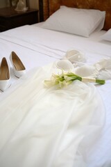 Beautifully arranged Elegant Bridal Attire resting on a bed alongside Shoes and vibrant Flowers