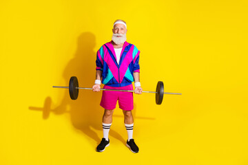 Full length photo banner of sportive cheerful old man lifting barbell dressed stylish retro sportswear isolated on yellow color background