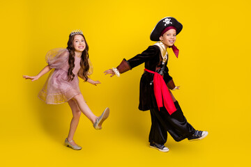 Full size photo of two little kids dancing halloween pirate princess costume isolated on yellow color background