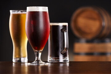 Glasses with different types of beer on wooden table in bar. Space for text