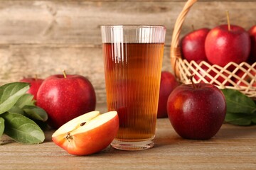 Glass of juice and apples on wooden table