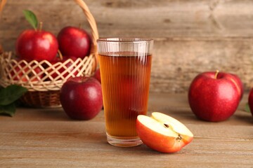 Glass of juice and apples on wooden table