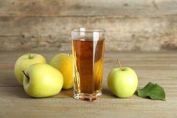 Glass of juice and apples on wooden table