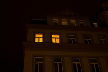 At night, the windows of a building are illuminated, casting light into the surrounding space and...