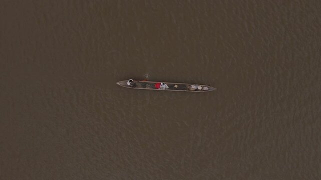 Aerial close-up view of a poler silhouetted rowing a Congo traditional canoe on the waterways of the Congo river