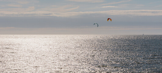 Two kitesurfer on the North Sea during sunset. Clear sky, extreme sport in Scheveningen, The Hague, Netherlands.