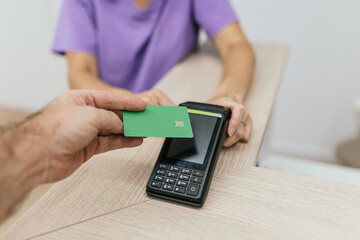 Patient making contactless payment using credit card at optometrist appointment