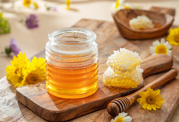 Natural organic honey in glass jar, honey dipper and honeycombs are near. Natural food background.