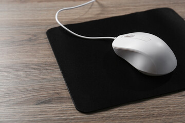 Computer mouse with mousepad on wooden table, closeup