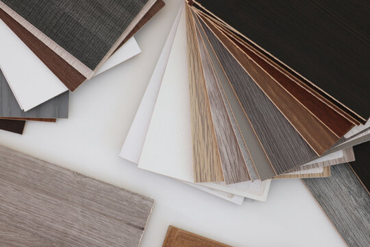 Different samples of wooden flooring on white table, top view