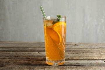 Fototapeta premium Glass of tasty refreshing drink and straw on wooden table against gray background